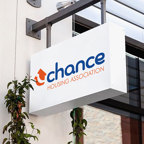 Brand Identity - Hanging sign on building with logo printed on it.